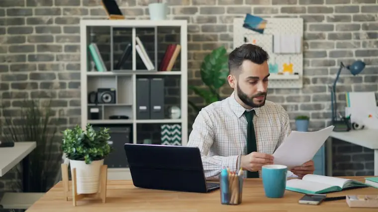 Accountant reviewing documents at a desk with a laptop