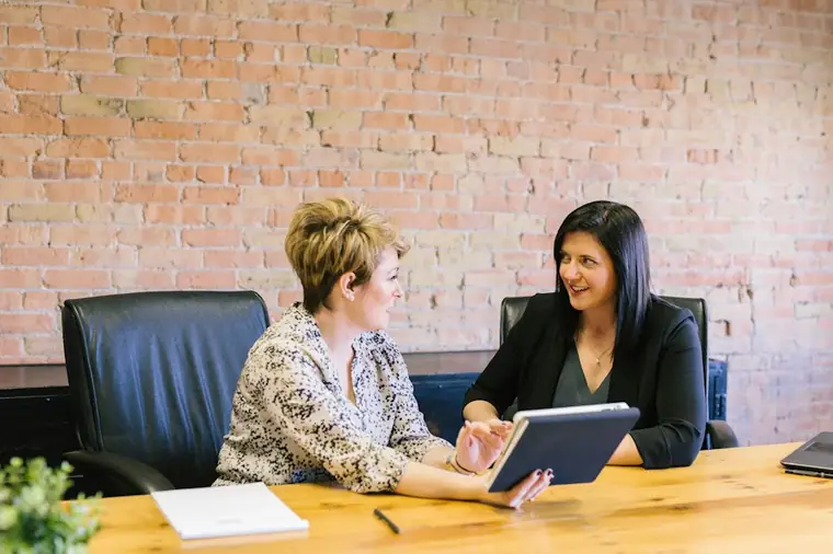 Two women talking across a table in a meeting room