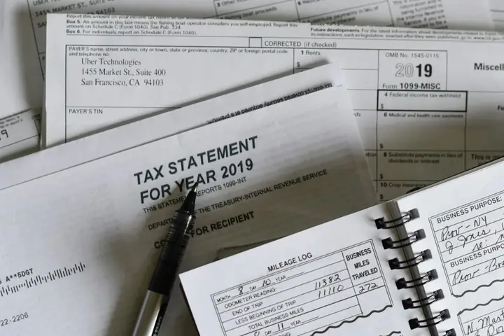 Pen resting on business tax forms and a mileage log