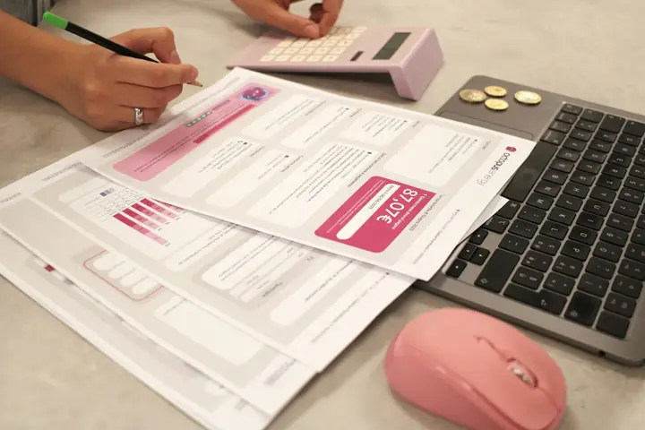 Payroll paperwork with a calculator and laptop