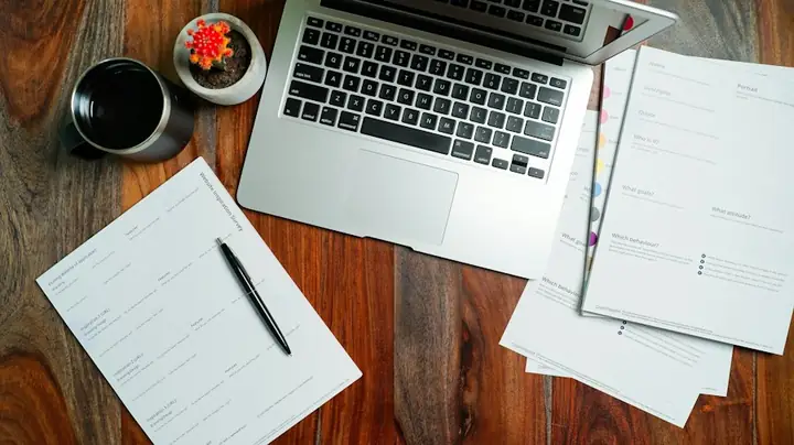 Laptop and paperwork on a wooden desk