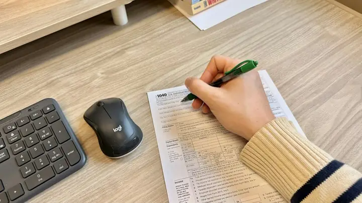 Hand writing notes on a document beside a keyboard